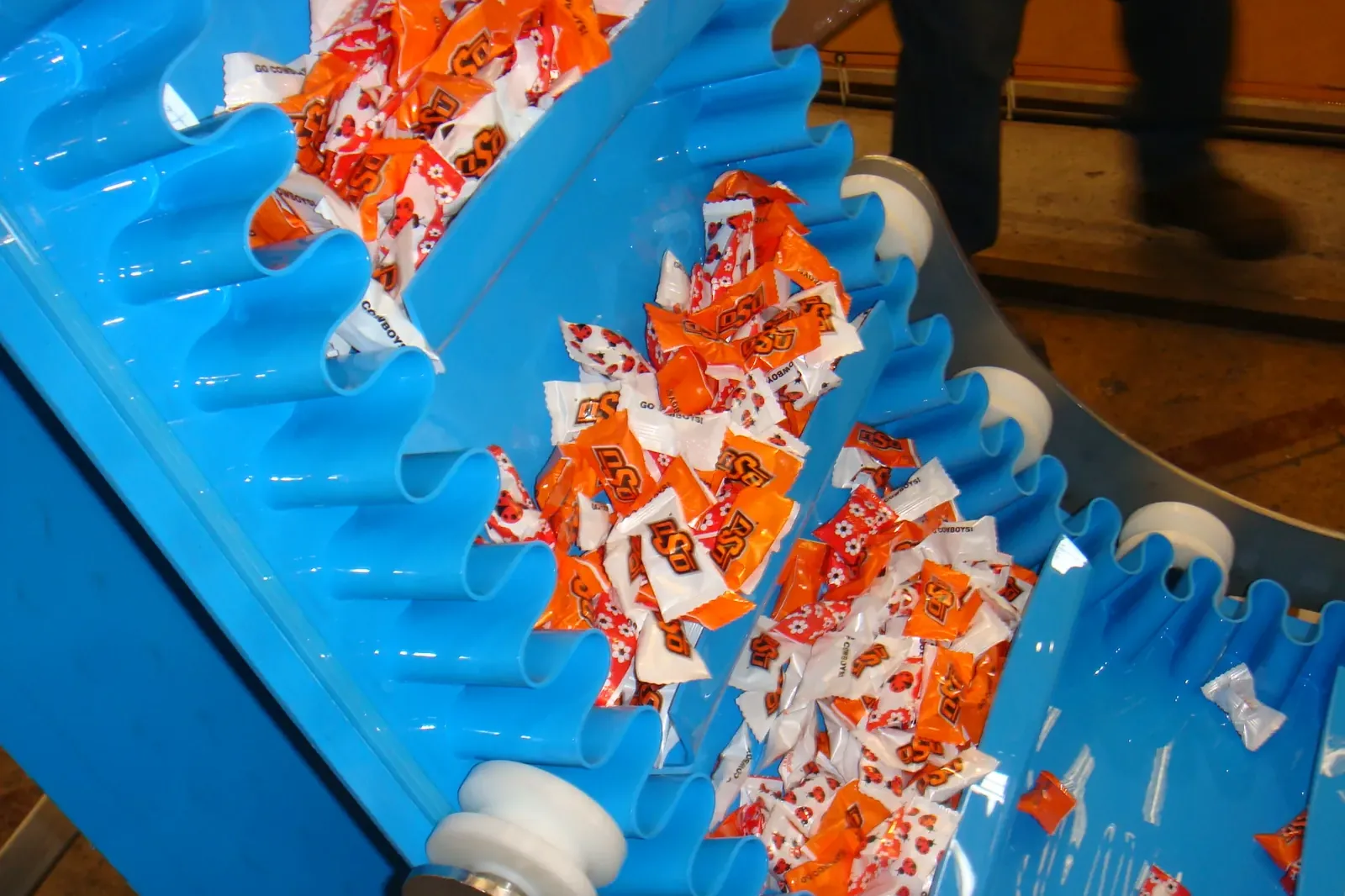 Cleated belt with sidewalls carrying wrapped sweets on an incline conveyor