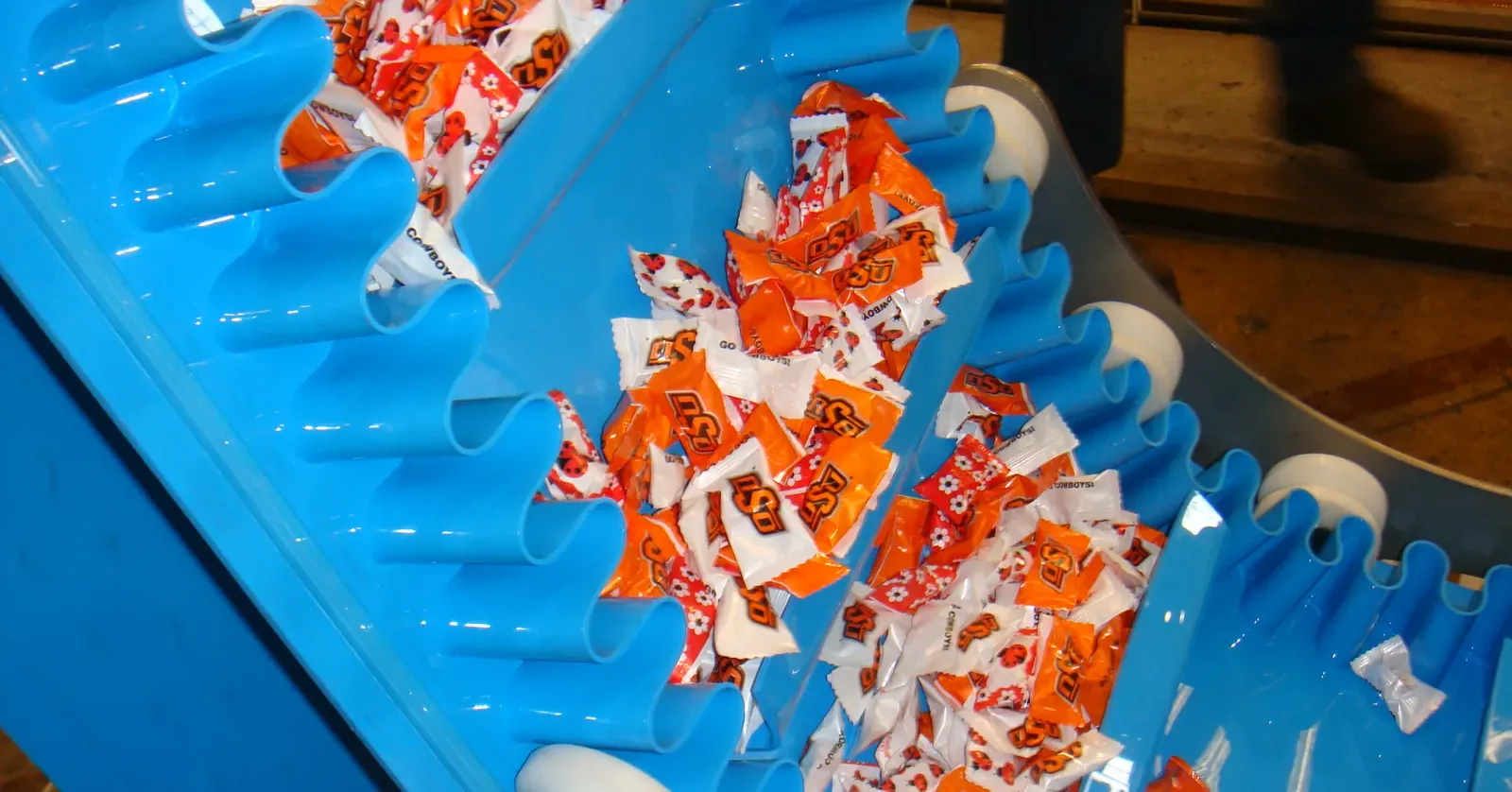 Cleated belt with sidewalls carrying wrapped sweets on an incline conveyor